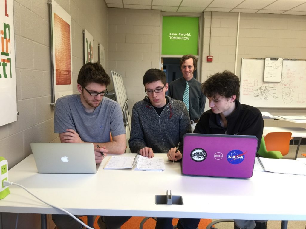 Graham Van Goffrier, Noah Ransom, and Logan Boyd (right to left) participate in the 2016 IEEEXtreme competition. Prof Vince Weaver (background) and Prof Yifeng Zhu (not shown) advised and proctored the competition.,